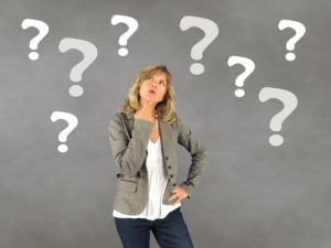 Woman wondering what the best coaching questions to ask are? Surrounded by question marks