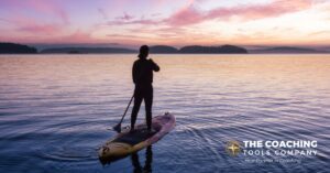 Client on paddle board enjoying summer life coaching exercise