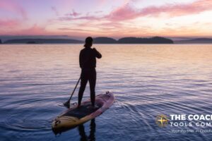Client on paddle board enjoying summer life coaching exercise