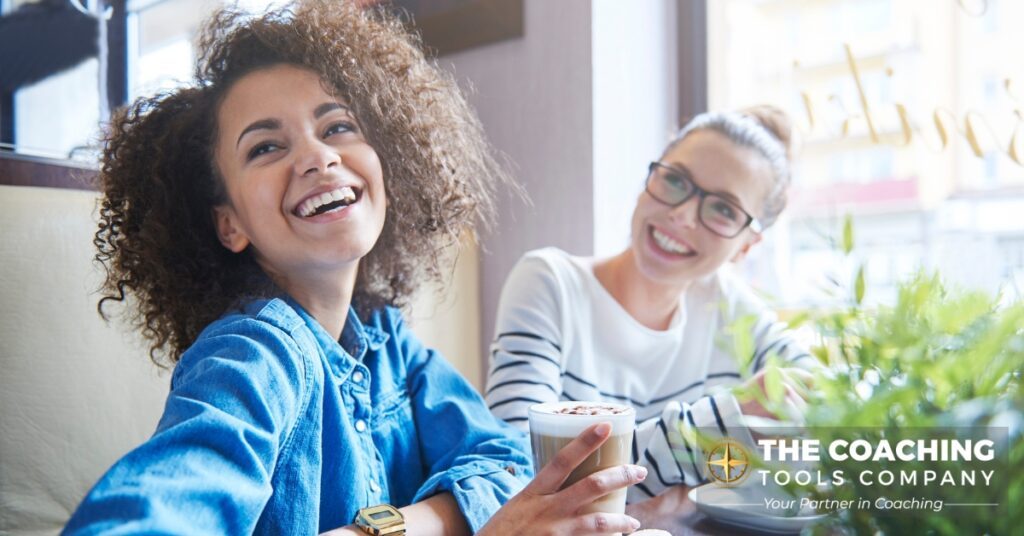 Two women smiling and sharing a coffee, symbolising gratitude, connection, and supportive relationships in coaching.