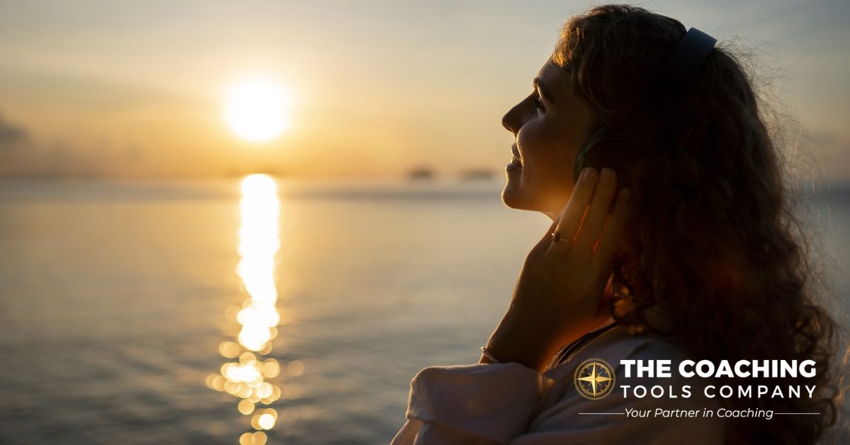 Woman on beach at sunrise with a gentle smile, symbolising reflection and mental well-being.
