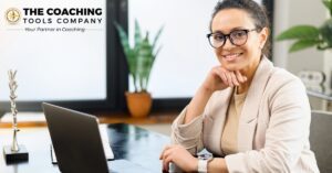 Professional woman working thoughtfully at a laptop, reflecting on her coaching niche